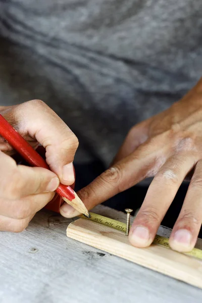 Joven haciendo una marca en una tira de madera — Foto de Stock