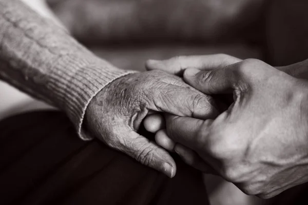 Junger Mann hält die Hand einer alten Frau — Stockfoto