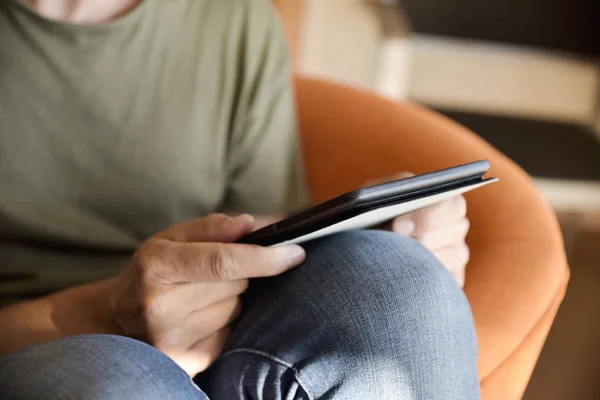 Jovem usando um tablet sentado em um sofá — Fotografia de Stock