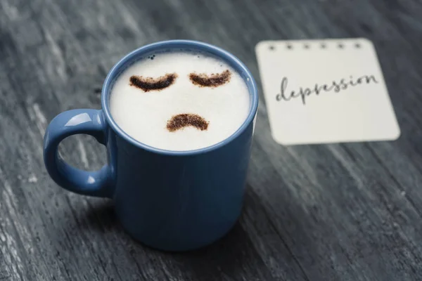 Cup of cappuccino with a sad fac — Stock Photo, Image