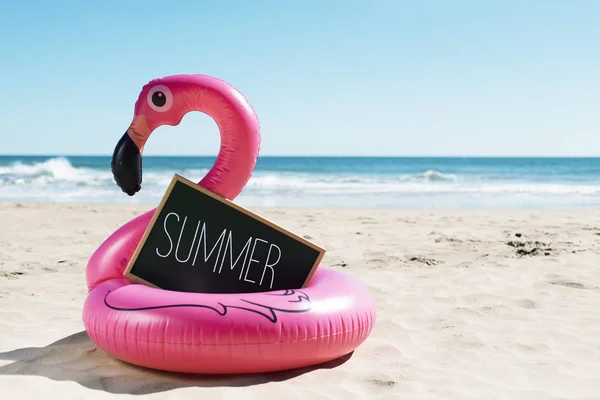 Flamingo simma ring på stranden och text sommaren — Stockfoto