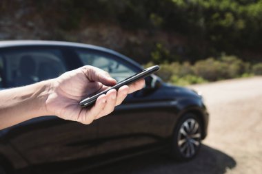 yolda bir araba yanındaki bir akıllı telefon kullanan adam