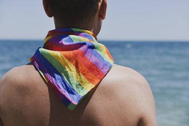 adam bir gökkuşağı bayrağı önünde Okyanusu ile