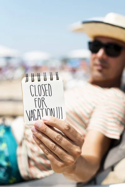 Man with a note with the text closed for vacatio — Stock Photo, Image