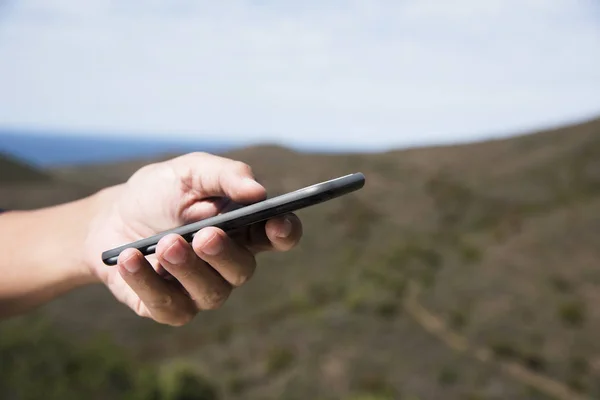 Man met behulp van een smartphone in de bergen — Stockfoto
