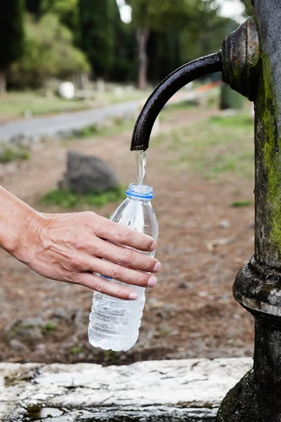 Man filling a bottle with water from a fountai — Stock Photo, Image