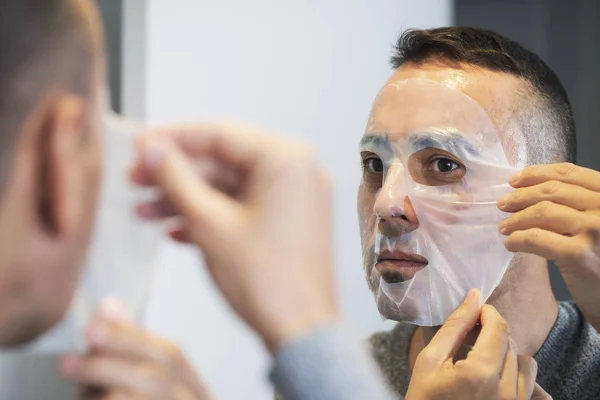 Man applicera en ansiktsmask på honom — Stockfoto