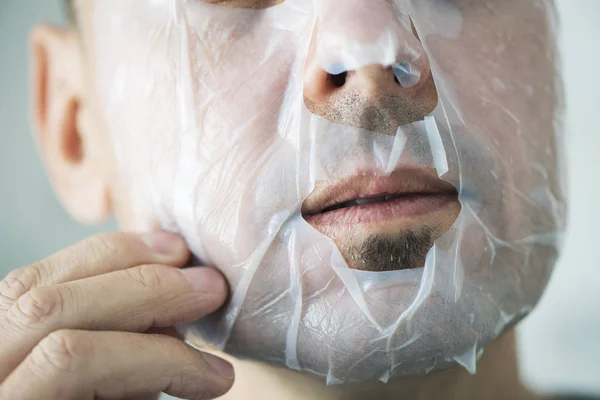 Мужчина наносит маску на лицо — стоковое фото