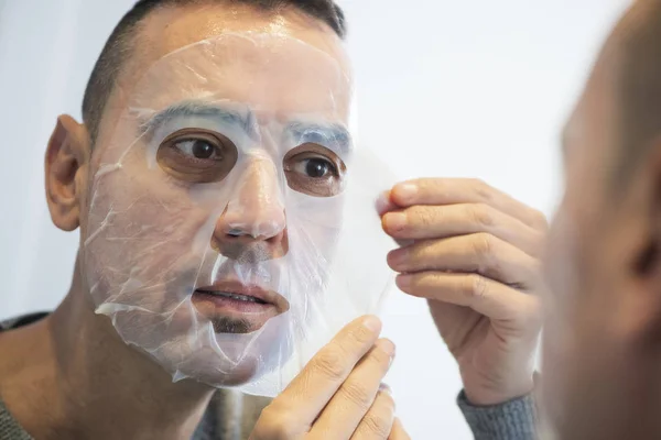 Hombre aplicando una máscara facial a sí mismo —  Fotos de Stock