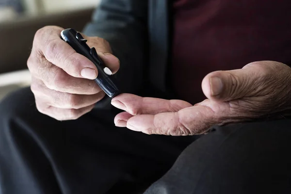 Old man about to measure his blood glucose level — ストック写真