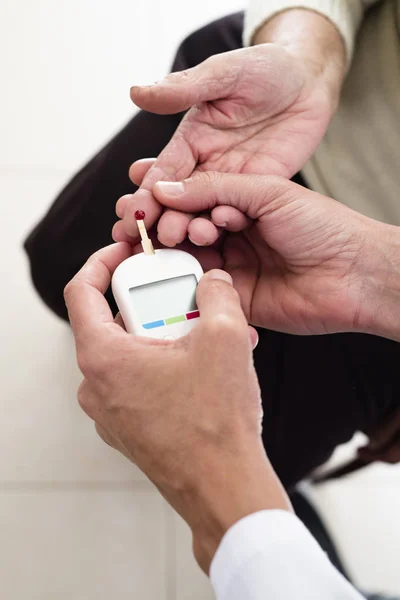 Measuring the blood glucose level of an old woman — ストック写真