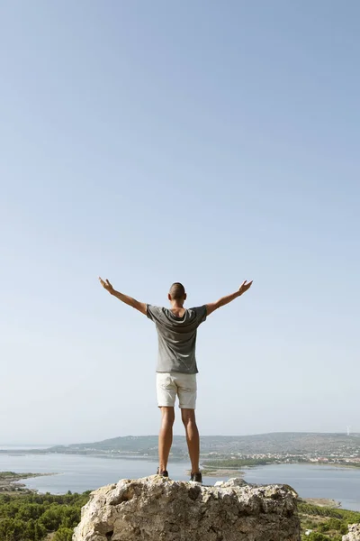 Homme avec les bras en l'air sur le dessus d'un rocher — Photo