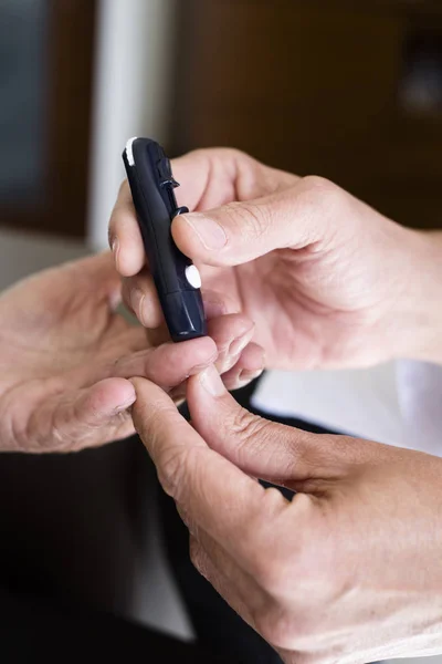 Measuring the blood glucose level of an old ma — ストック写真