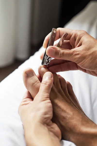 Junger Kaukasier schneidet sich die Fußnägel — Stockfoto