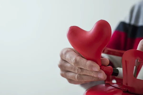 Inflating a heart-shaped balloon from a cylinder — Stock Photo, Image