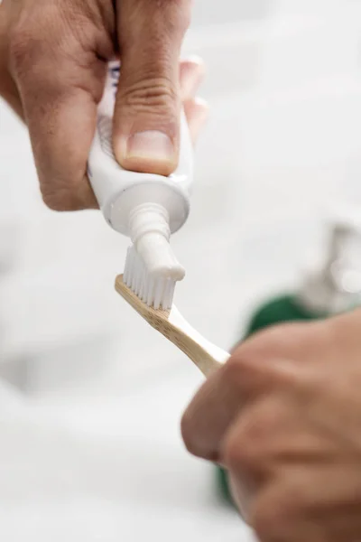 Hombre usando un cepillo de dientes de bambú en el baño — Foto de Stock