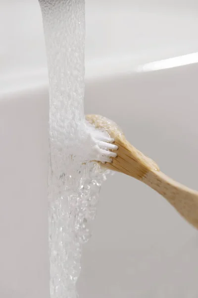 Man met een bamboe tandenborstel in de badkamer — Stockfoto