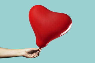 Kırmızı kalp şeklinde balonu olan bir adam.