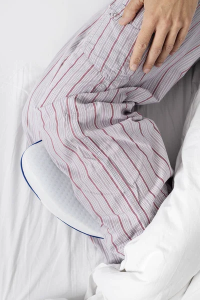 Man in bed using an anatomical leg cushion — Stock Photo, Image