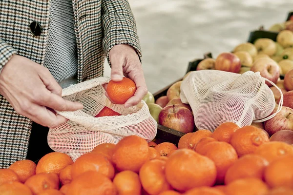 Uomo che utilizza una borsa a rete riutilizzabile in un fruttivendolo — Foto Stock