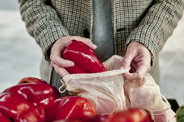 Adam manavda yeniden kullanılabilir ağ torbası kullanıyor. — Stok fotoğraf