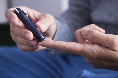 Adam kan şekeri seviyesini ölçmek üzere.