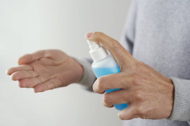 Kafkasyalı bir adamın mavi el dezenfektanı ile ellerini dezenfekte ettiği yakın plan.