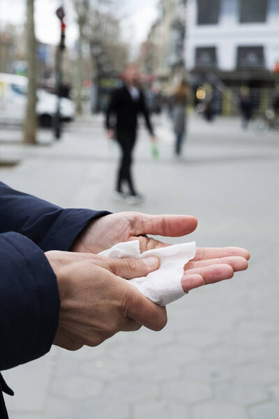 closeup of a caucasian man on the street disinfecting his hands with a wet wipe