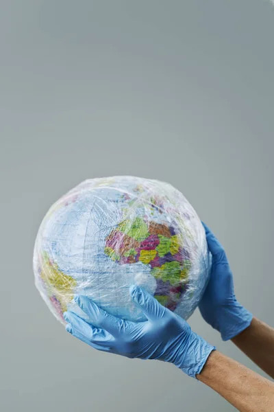 Médico Con Guantes Quirúrgicos Azules Que Sostiene Mundo Envuelto Plástico — Foto de Stock