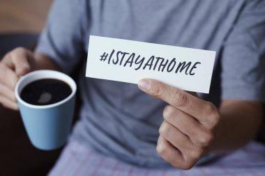 closeup of a man, in pajamas, showing the message #Istayathome written in a piece of paper, as a measure to stop the spreading of the covid-19 clipart
