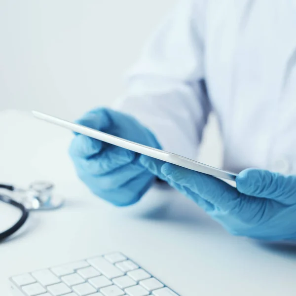 외투를 수술용 장갑을 책상에 디지탈 태블릿을 사용하는 의사의 — 스톡 사진