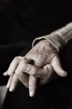 Son sınıf beyaz bir kadının elini tutan genç beyaz bir adamın, parmakları sepia tonlama ile birbirine dolanmış.