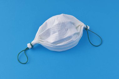 Mavi arka planda kağıt havlu ve lastik bantlardan yapılmış ev yapımı yüz maskesi.