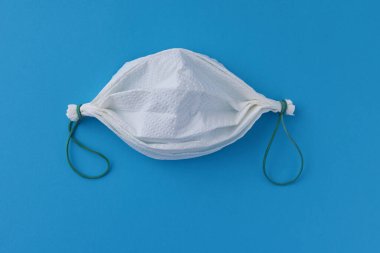 Mavi arka planda kağıt havlu ve lastik bantlardan yapılmış ev yapımı yüz maskesi.