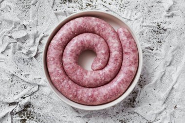 high angle view of a rolled botifarra, a pork meat sausage typical of Catalonia, Spain, in a plate, on a white textured textile background clipart