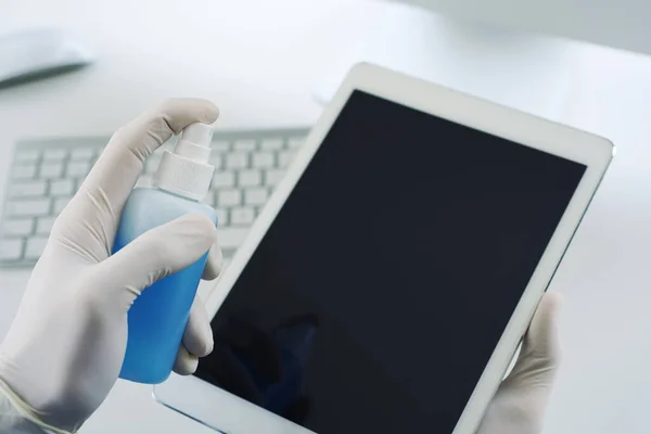 책상에 라텍스 장갑을 살균제를 자신의 디지털 태블릿을 소독하는 — 스톡 사진