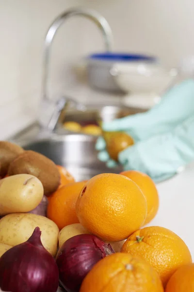 厨房里一个男人的特写镜头 戴着手套 洗一些刚购买的水果和蔬菜 用清水和食品清洁剂在水池里 — 图库照片