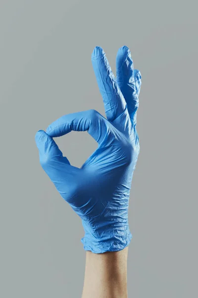 Closeup Hand Man Wearing Blue Surgical Gloves Doing Sign Gray — Stock Photo, Image