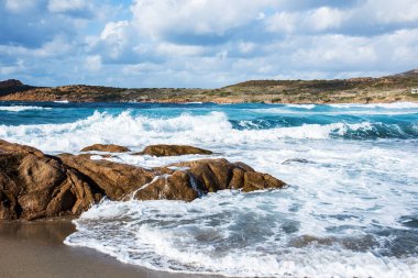La Marinedda sahilinde, Isola Rossa 'da, Sardunya' da, İtalya 'da güçlü bir dalgayla akdeniz ve kaya oluşumlarının manzarası.