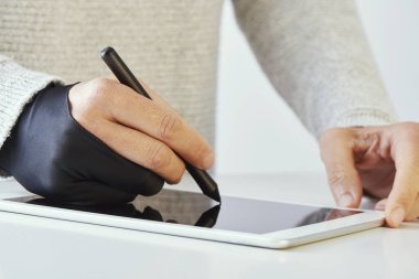 closeup of a caucasian man wearing a black two finger glove while is using a graphic pen in a digital tablet clipart