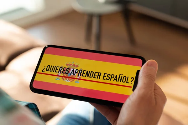 일상적 실내에서 의자에 스마트폰을 코카서스 남성의 화면에 스페인어로 배우고 으세요 — 스톡 사진