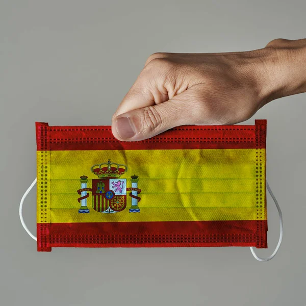 Close Homem Segurando Uma Máscara Cirúrgica Padronizada Com Bandeira Espanha — Fotografia de Stock