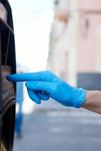 一名戴着蓝色胶乳手套 在街上使用电子泊车表的年轻人的特写镜头 — 图库照片