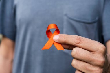 closeup of a young caucasian man with an orange ribbon in his hand, in support of people affected by multiple sclerosis clipart