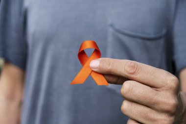 closeup of a young caucasian man with an orange ribbon in his hand, in support of people affected by multiple sclerosis clipart