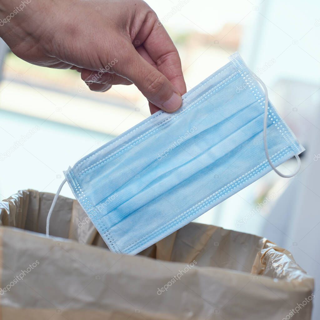 closeup of a man throwing a surgical mask to the trash can