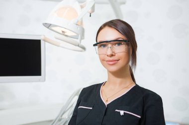 Tıbbi ofis arka plan üzerinde mutlu genç kadın diş hekimi