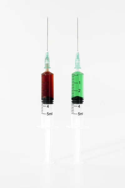 白で単離された赤と緑の血清を有する2本の注射器 — ストック写真