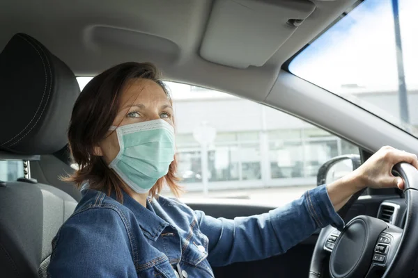 Woman driving her car with a mask on her face