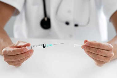 Steteskoplu bir kadın doktorun elinde şırınga.
